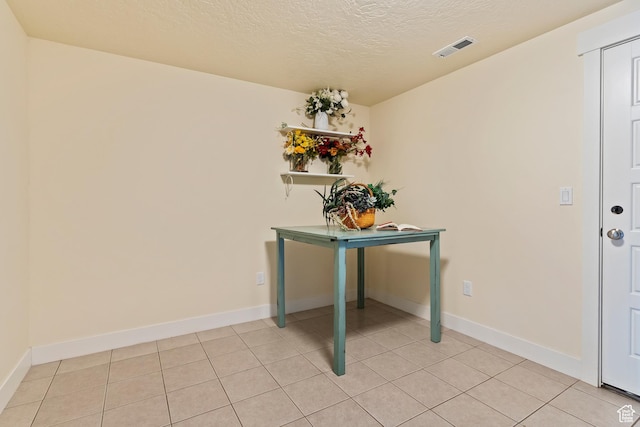 foyer with a textured ceiling, light tile patterned flooring, and baseboards
