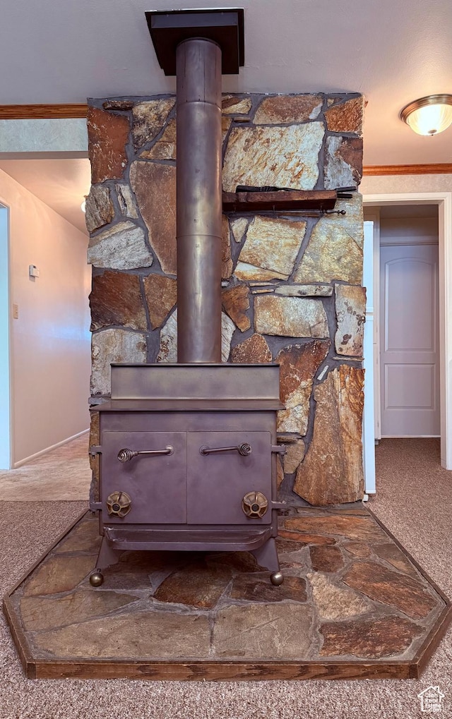 detailed view of a wood stove, carpet, baseboards, and ornamental molding