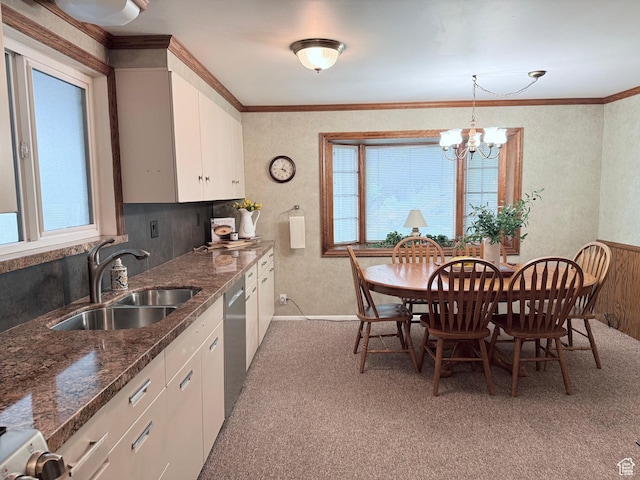 kitchen with a sink, healthy amount of natural light, light colored carpet, a chandelier, and ornamental molding