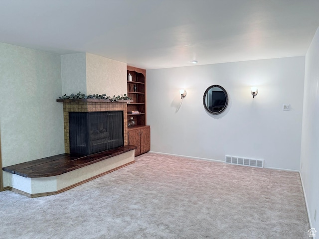 unfurnished living room featuring a fireplace, carpet floors, built in shelves, and baseboards