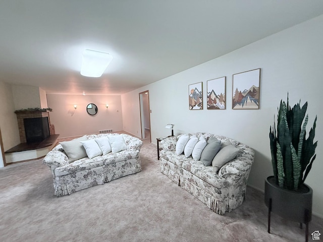 living area featuring carpet floors and a fireplace with raised hearth