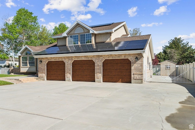 view of front facade with solar panels, concrete driveway, and a shingled roof