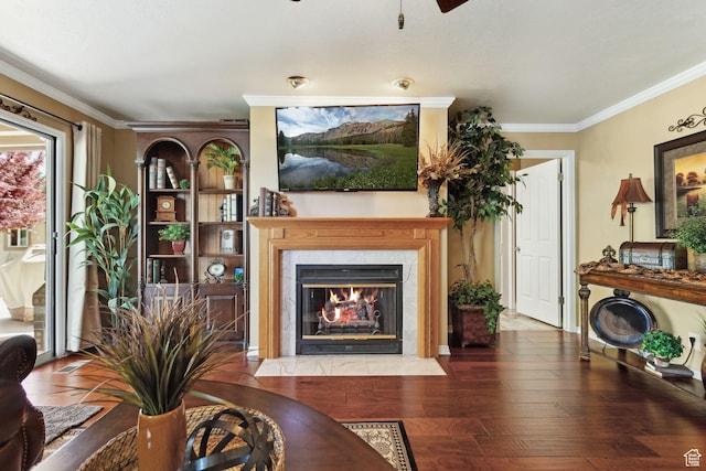 living room with crown molding, a ceiling fan, a high end fireplace, and wood-type flooring