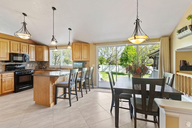 kitchen featuring black appliances, a sink, backsplash, a kitchen breakfast bar, and light tile patterned floors