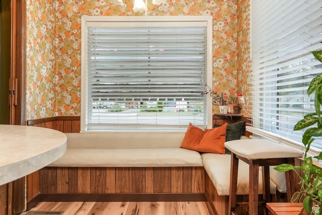 living area featuring wallpapered walls, a wainscoted wall, and wood finished floors