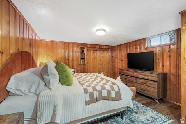 bedroom featuring wooden walls, wood finished floors, and a textured ceiling