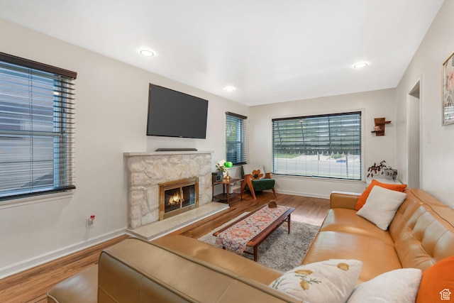 living room with wood finished floors, baseboards, a fireplace, and recessed lighting
