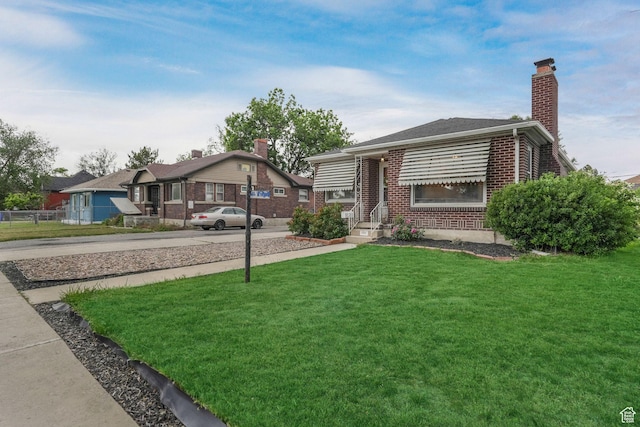 view of front of property with brick siding, a chimney, and a front lawn