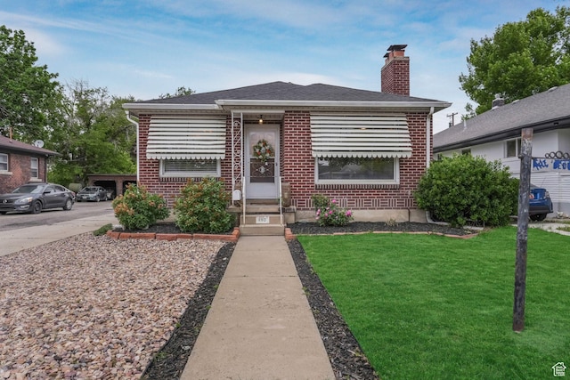 bungalow with brick siding, a chimney, a front lawn, and entry steps