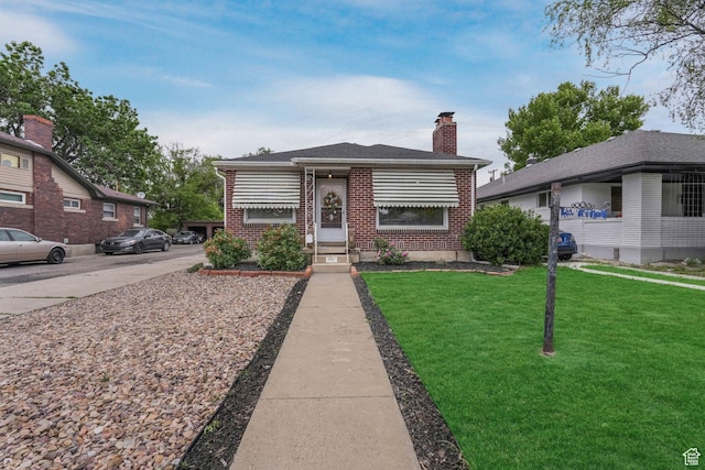 view of front of home with brick siding, a chimney, and a front yard