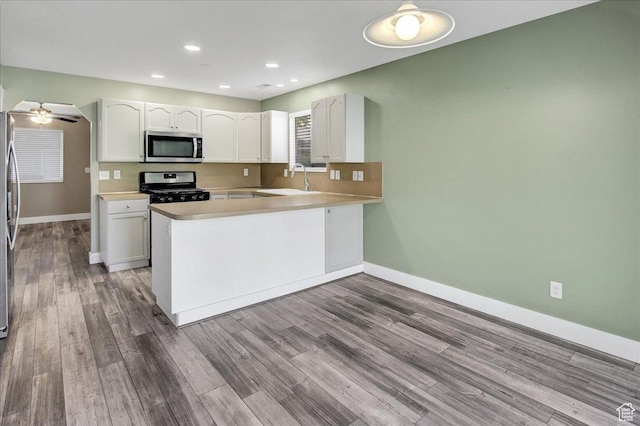 2421 N 400 E Unit M-1, North Ogden, UT 84414 - kitchen with appliances with stainless steel finishes, white cabinets, baseboards, a peninsula, and wood finished floors
