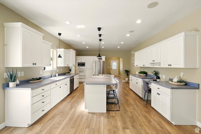 2897 W 3400 N, Benson, UT 84335 - kitchen with arched walkways, appliances with stainless steel finishes, a sink, a breakfast bar, and white cabinetry