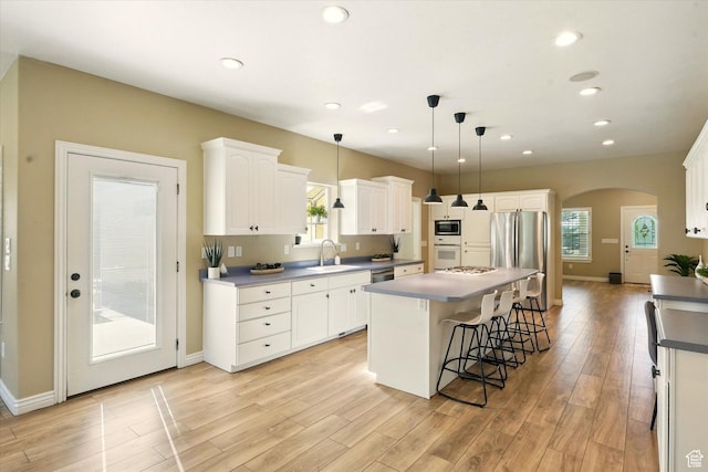 2897 W 3400 N, Benson, UT 84335 - kitchen featuring a sink, appliances with stainless steel finishes, arched walkways, a center island, and light wood-style flooring