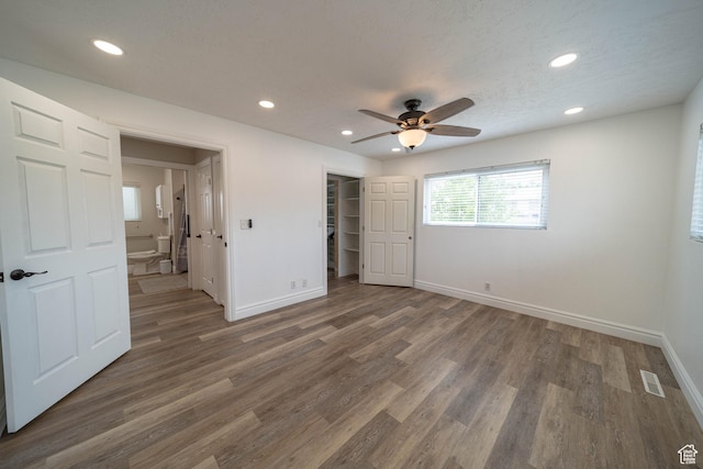 unfurnished bedroom featuring baseboards, recessed lighting, wood finished floors, a ceiling fan, and a spacious closet