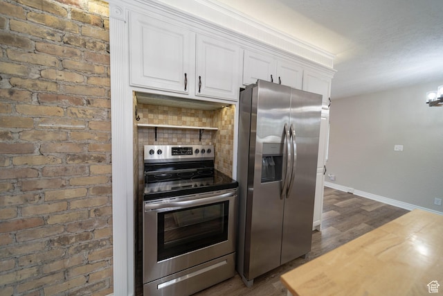 kitchen with appliances with stainless steel finishes, dark wood-type flooring, white cabinets, baseboards, and tasteful backsplash