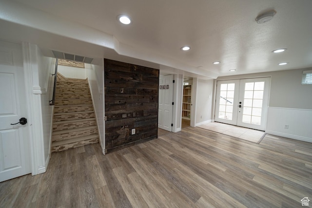unfurnished living room with french doors, wood finished floors, stairs, baseboards, and recessed lighting