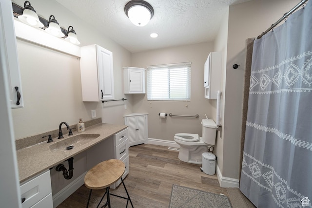 full bathroom with toilet, wood finished floors, a textured ceiling, baseboards, and curtained shower