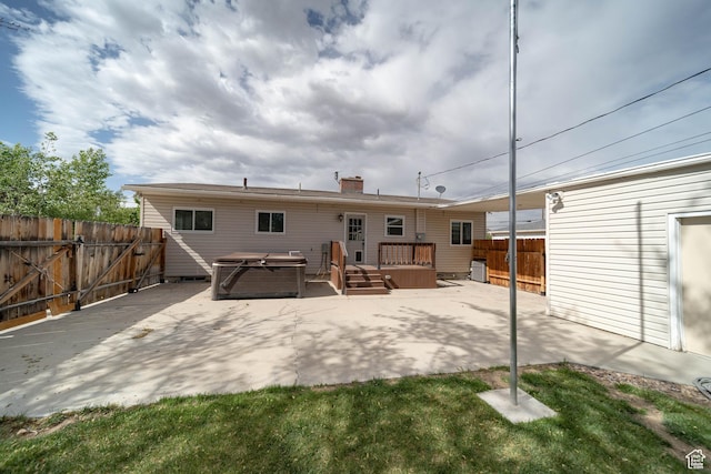rear view of house featuring a fenced backyard, a patio, a wooden deck, and a hot tub
