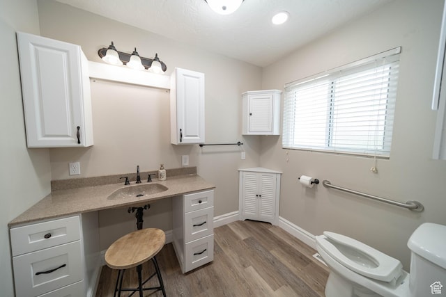 bathroom featuring toilet, wood finished floors, baseboards, and vanity