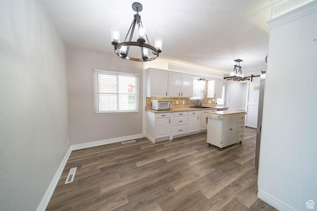 kitchen featuring a chandelier, white microwave, a sink, and baseboards