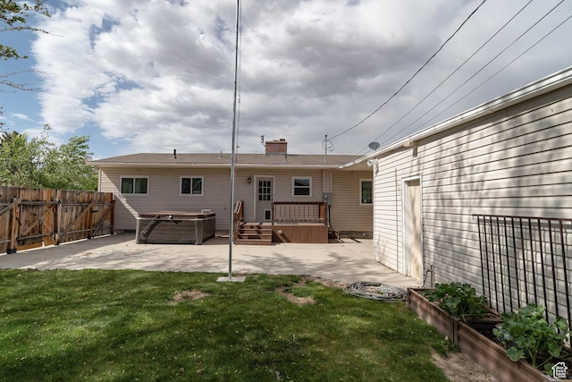back of property featuring a hot tub, a patio area, a chimney, and a wooden deck
