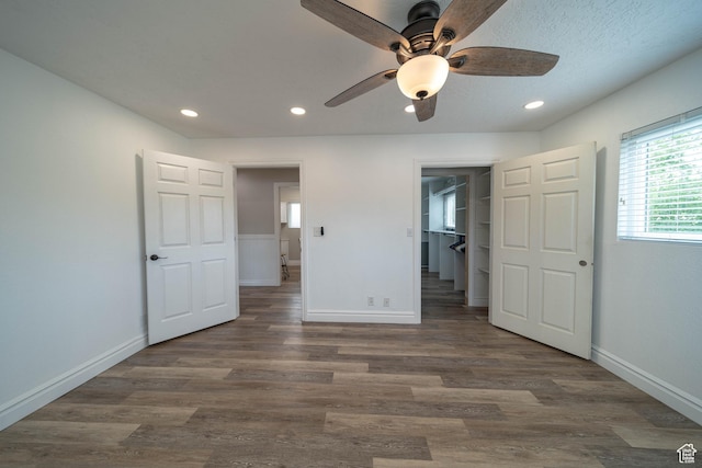 unfurnished bedroom with baseboards, wood finished floors, recessed lighting, a walk in closet, and a ceiling fan
