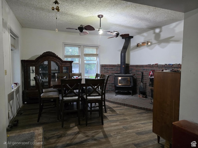 dining space with ceiling fan, a wood stove, a textured ceiling, and wood finished floors