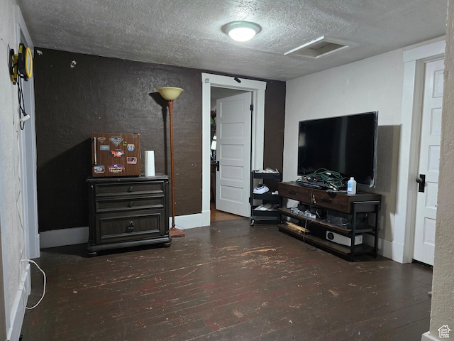living area featuring attic access, a textured ceiling, hardwood / wood-style floors, and a textured wall