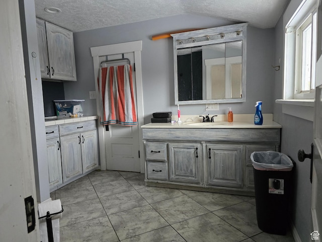 bathroom with a textured ceiling, vanity, and marble finish flooring