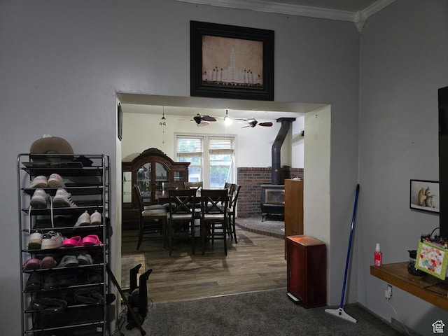 dining room with a wood stove, ornamental molding, wood finished floors, and carpet flooring