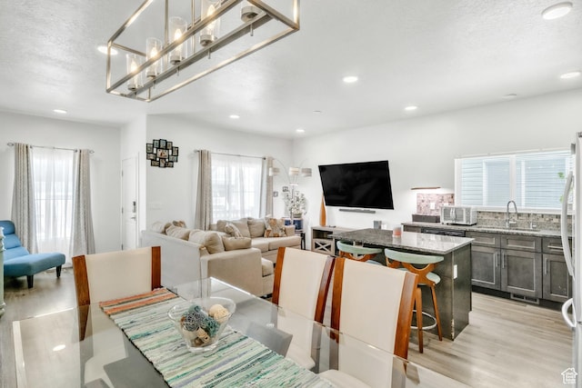 dining room featuring light wood-type flooring, recessed lighting, and a textured ceiling