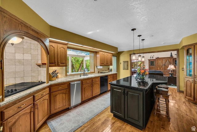 305 S Rachel Ln, New Harmony, UT 84757 - kitchen featuring a breakfast bar area, black appliances, a textured ceiling, light wood-style flooring, and a sink