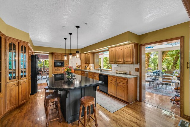 305 S Rachel Ln, New Harmony, UT 84757 - kitchen with black appliances, a textured ceiling, a sink, a kitchen island, and healthy amount of natural light