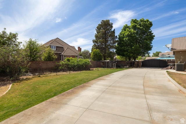 view of yard featuring central AC unit and concrete driveway