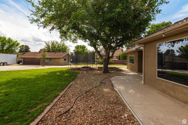 view of yard with a trampoline and driveway
