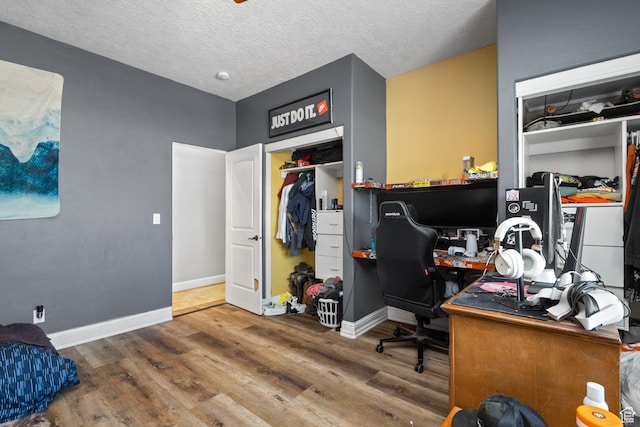home office featuring wood finished floors, baseboards, and a textured ceiling