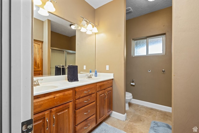 bathroom with a shower stall, toilet, double vanity, baseboards, and tile patterned floors