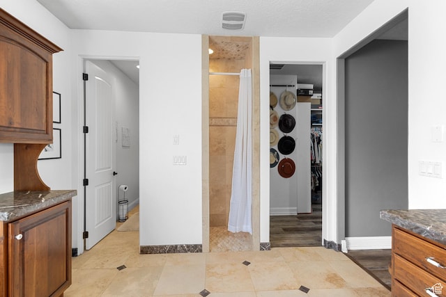 full bathroom featuring a stall shower, vanity, a spacious closet, and baseboards