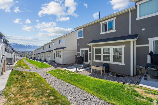 rear view of house featuring a mountain view, stucco siding, and a lawn