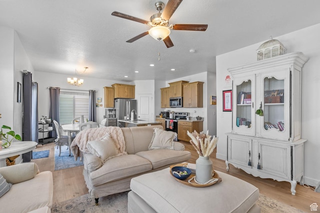 living area featuring a chandelier, light wood-type flooring, ceiling fan, recessed lighting, and a textured ceiling