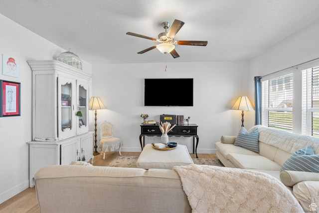 living room featuring a ceiling fan, light wood finished floors, and baseboards