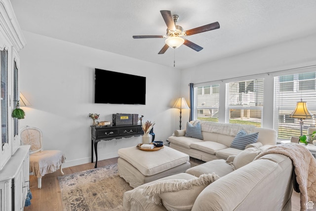 living area with plenty of natural light, a ceiling fan, wood finished floors, and baseboards