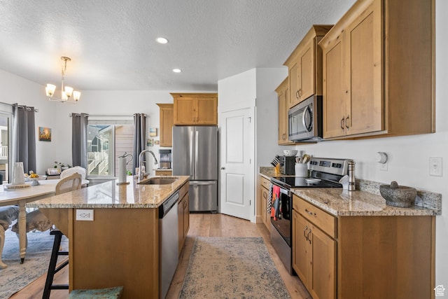 kitchen featuring stainless steel appliances, a sink, light wood-style flooring, a chandelier, and a textured ceiling