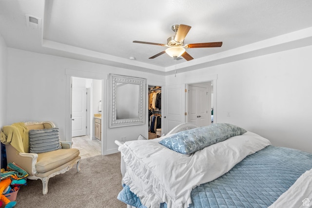 bedroom featuring a tray ceiling, a spacious closet, a closet, and light carpet
