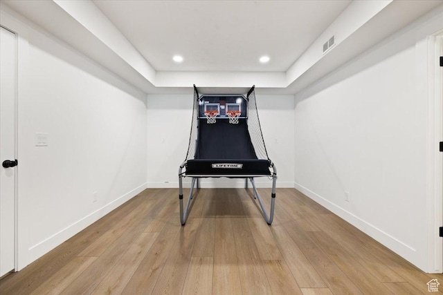 rec room with light wood-style floors, baseboards, recessed lighting, and a tray ceiling
