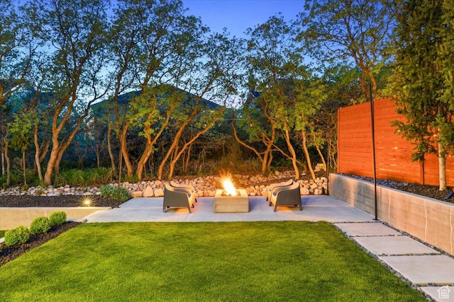 view of grassy yard featuring an outdoor fire pit, a patio, and a mountain view