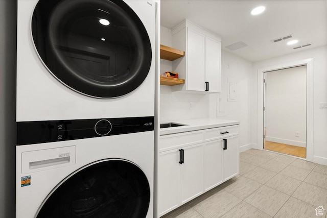 laundry area featuring estacked washer and dryer, cabinet space, baseboards, and recessed lighting