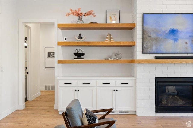 living room with light wood finished floors, a fireplace, and baseboards