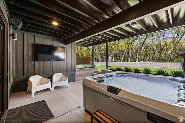 view of patio / terrace with a hot tub and view of wooded area