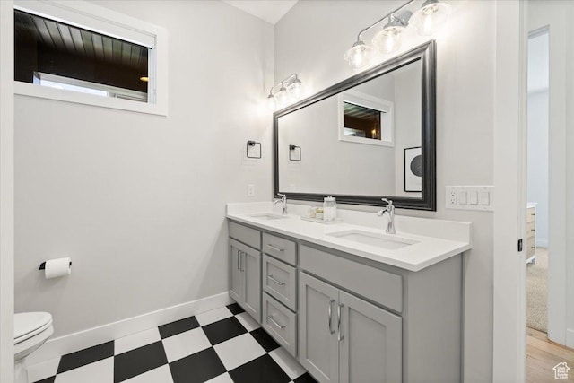 bathroom with tile patterned floors, baseboards, toilet, and double vanity